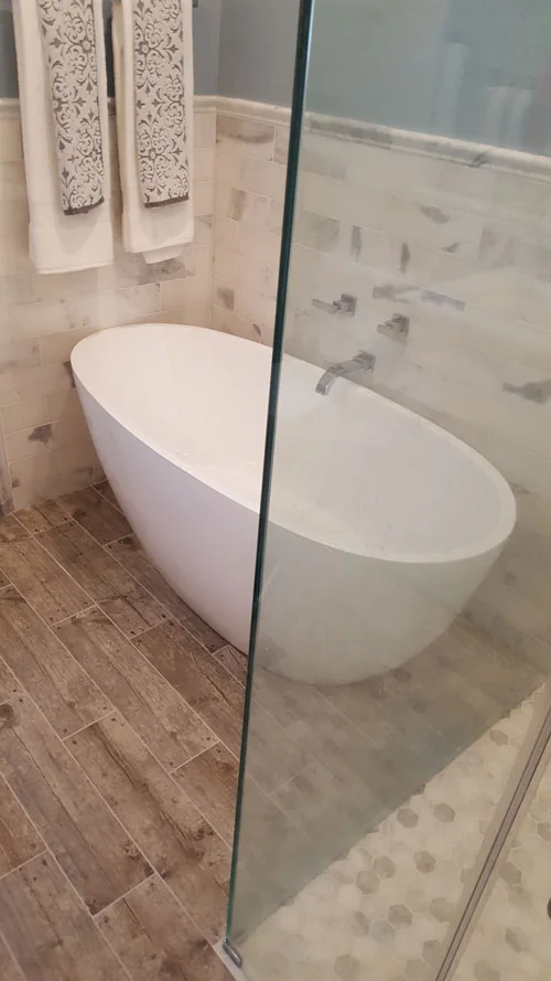 Freestanding soaking tub beside a glass shower in a renovated bathroom