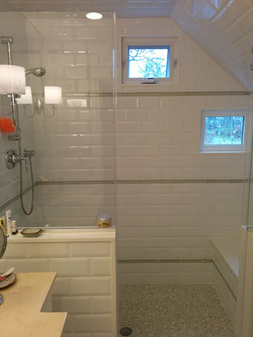 Shower under a sloped ceiling with subway tile and pebble floor