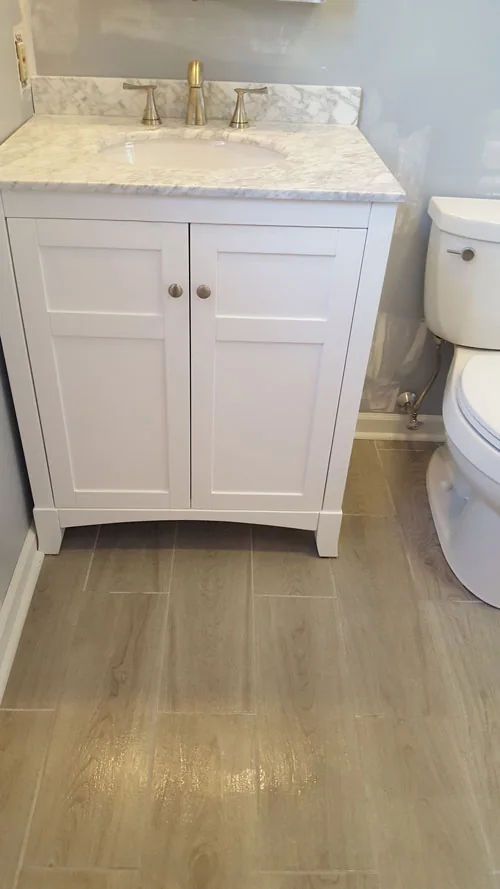 Bathroom with new white vanity, marble top and wood-look tile floor