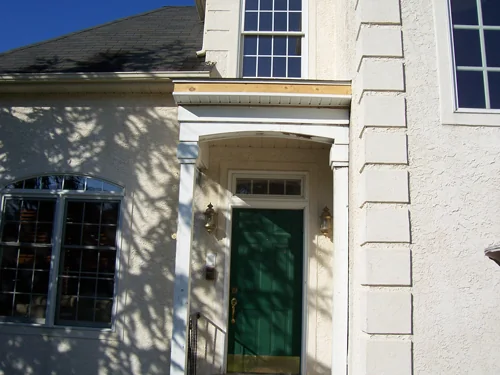 Renovated home exterior with a new green front door and stucco entry