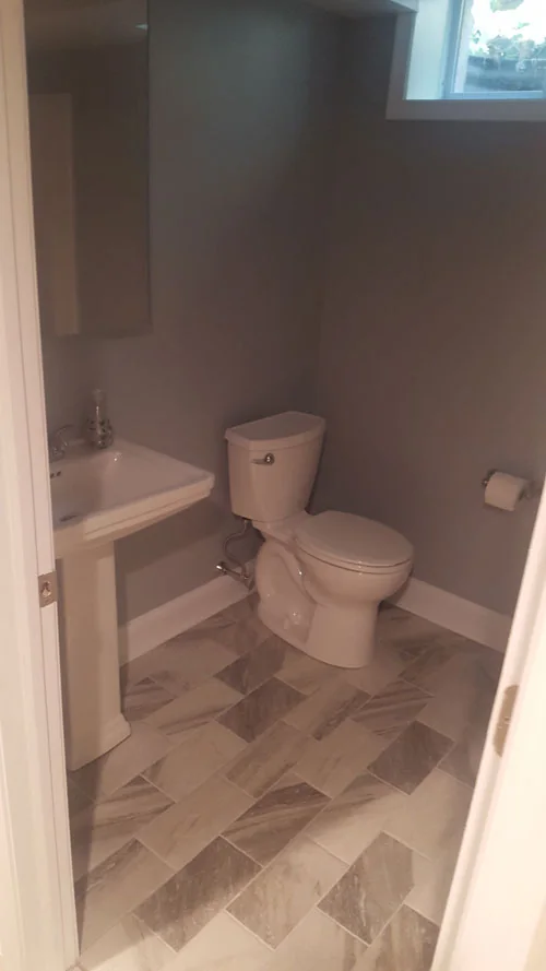 New basement powder room with pedestal sink and tile floor